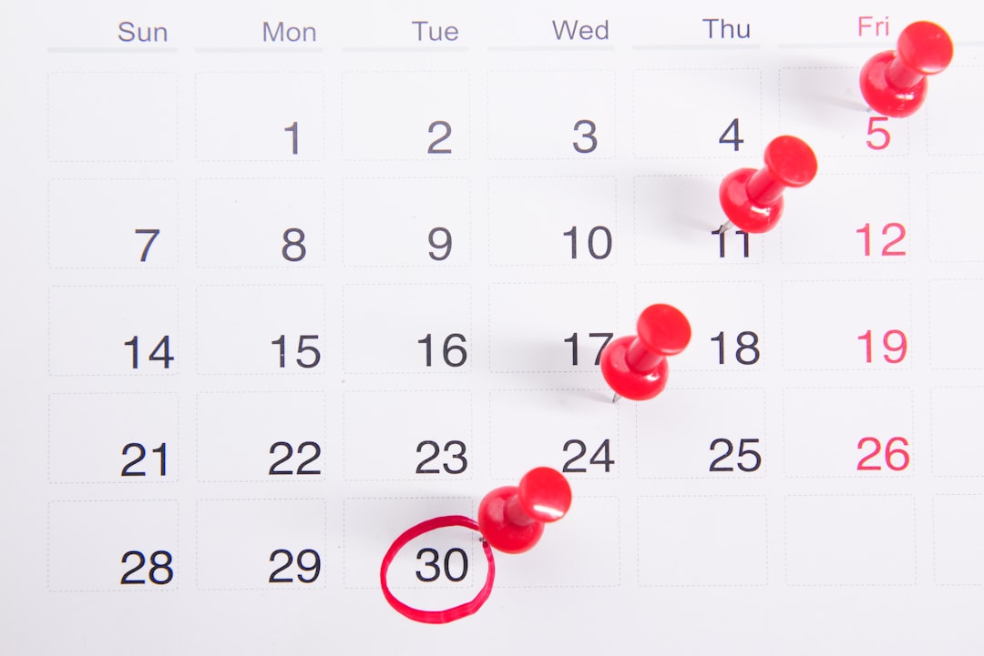 A calendar with the 30th day circled in red. Red pins poking different dates.