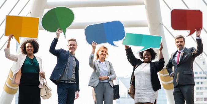 A group of 5 people, holding speech bubbles. Two white men. One white woman. Two black women.