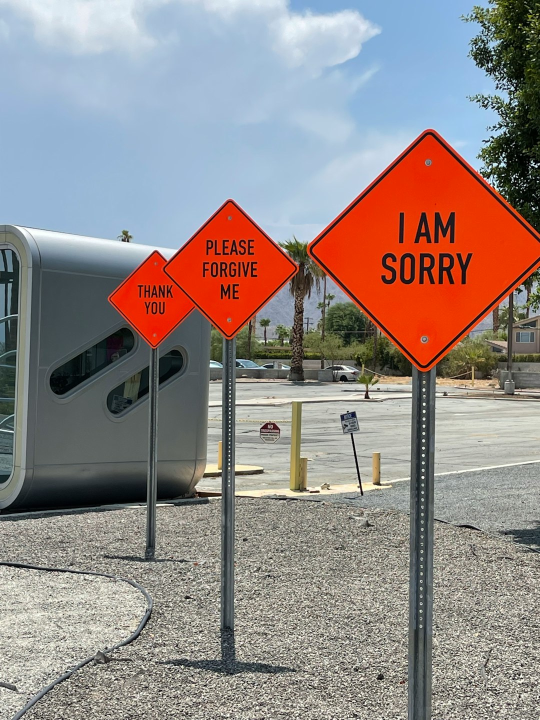 Three fake traffic sign with orange background and black lettering stating I am sorry, Please forgive me, and Thank you.